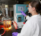 A researchers uses a machine to monitor a glass jar of lquid.